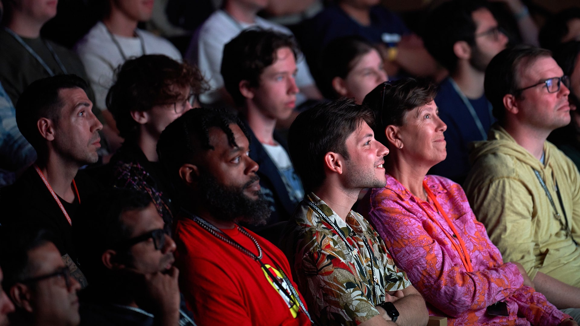 Members of an audience sit in a theater looking at a presentation. 