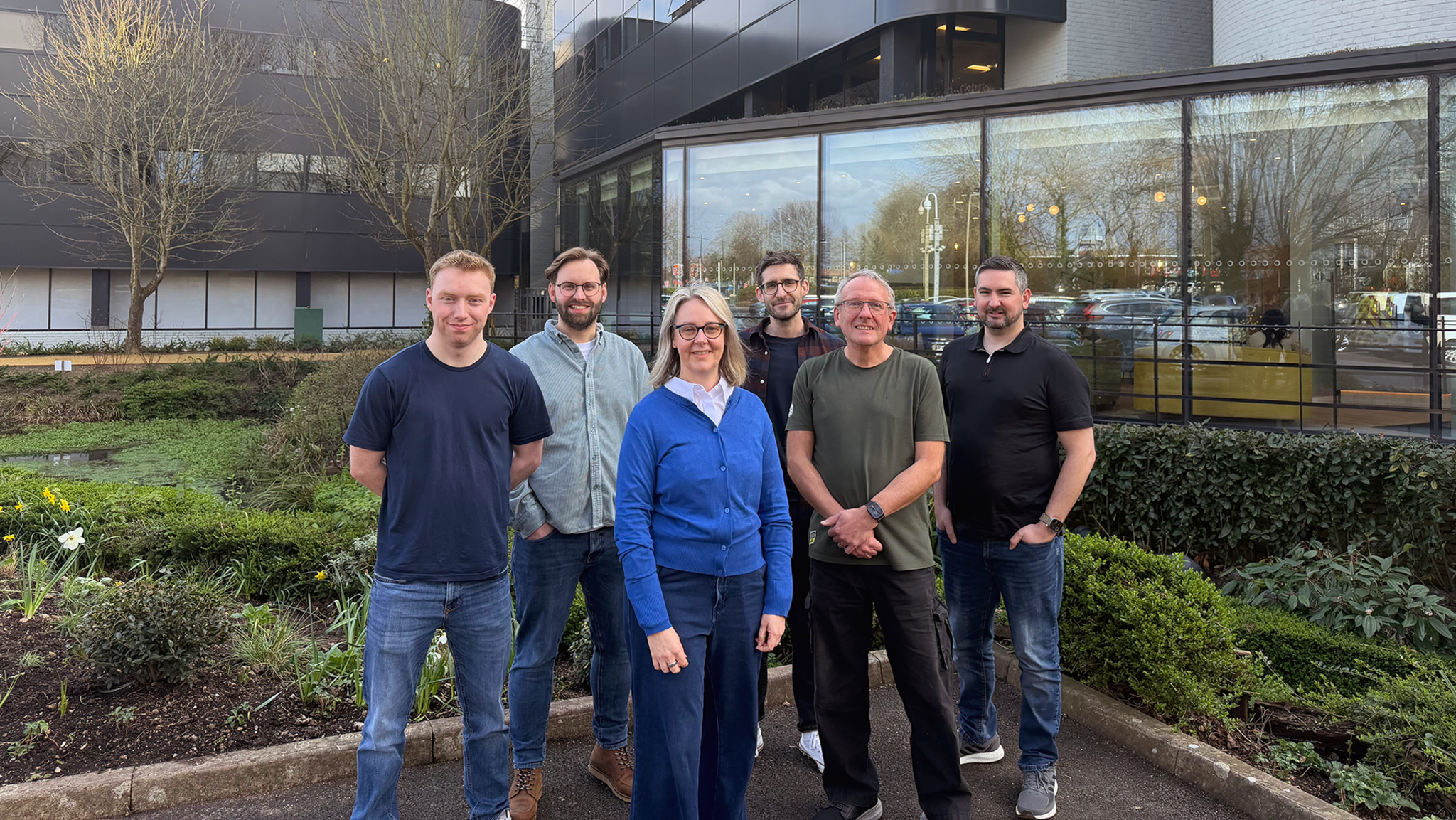 A photo of six members of the Plane Finder team, all standing outside in a courtyard next to an office building.