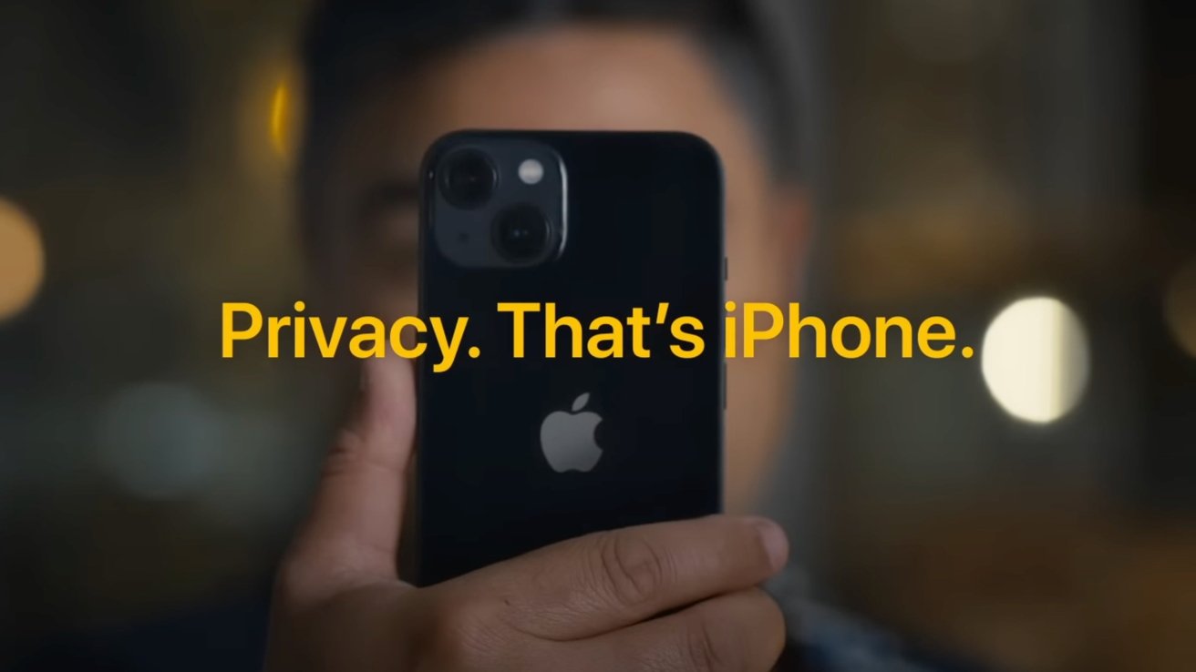 Person holding a black iPhone close to their face in a dim setting, with bold yellow text across the screen reading Privacy. Thats iPhone