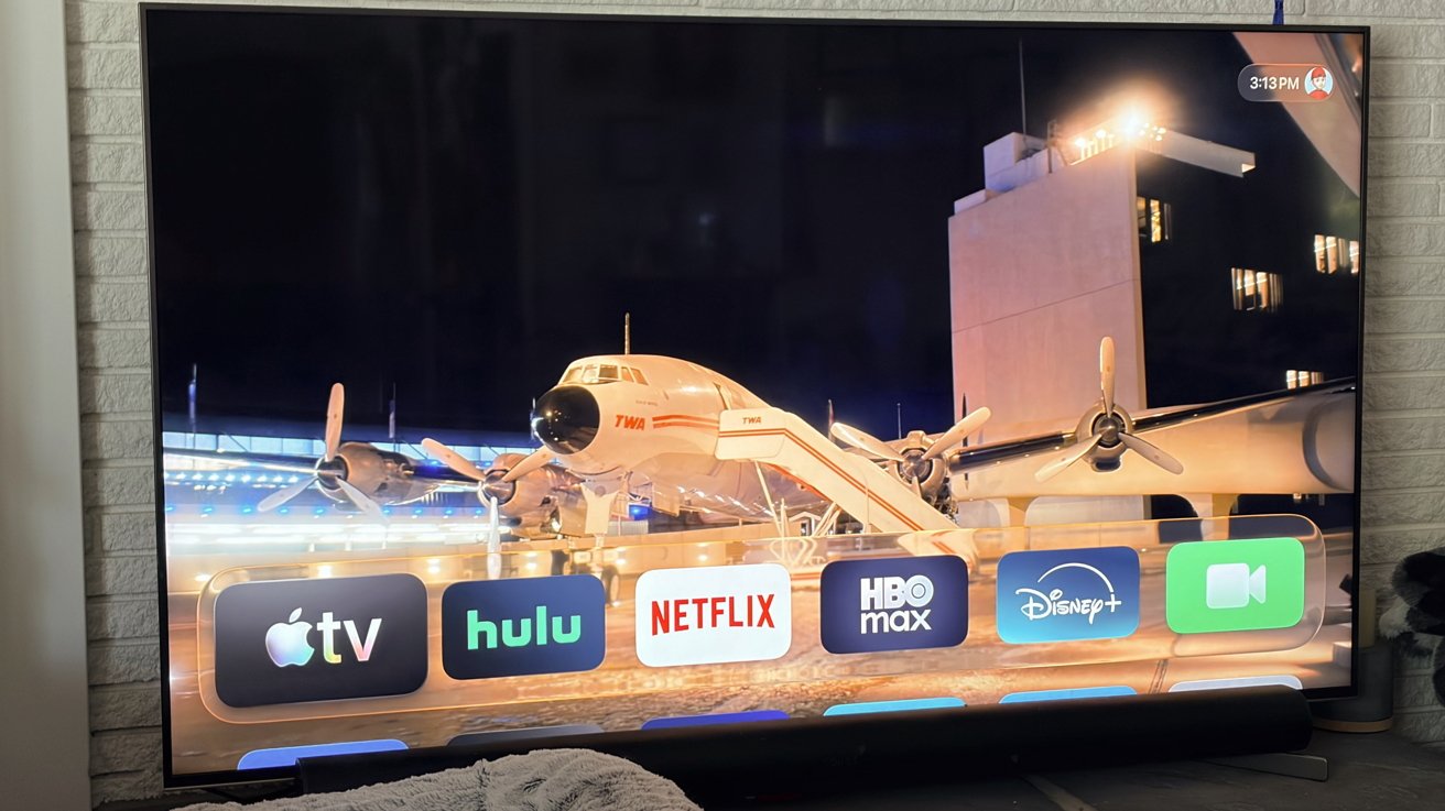 Large TV screen displaying a nighttime scene with a vintage airplane at an airport, and a bottom row of streaming app icons including Apple TV, Hulu, Netflix, HBO Max, Disney Plus